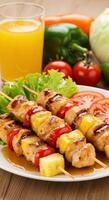 Delicious Grilled Chicken and Pineapple Skewers with fresh vegetables and juice photo