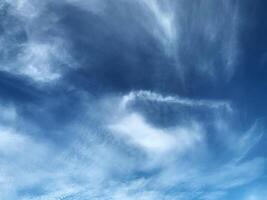 A clear blue sky with soft, wispy clouds drifting gently, creating a calm and peaceful atmosphere photo