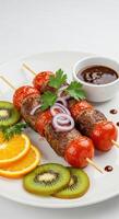 meat skewers with vegetables and orange slices on a white plate photo