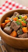 Delicious Beef Stew Recipe with Carrots and Mushrooms in Wooden Bowl photo