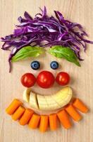 A charming face crafted from colorful fruits and vegetables, showcasing healthy food art on wood. photo