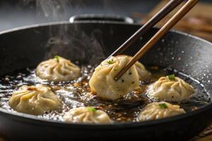 Steaming dumplings being pulled from a pan with chopsticks. photo
