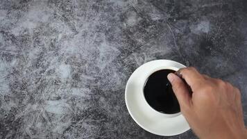 Man hand move the spoon for swing coffee in cup top view dark background video