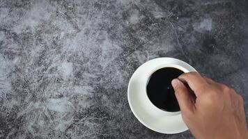 Man hand move the spoon for swing coffee in coffee cup top view dark background video
