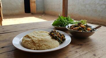 A table with two plates of food and a bowl of greens photo