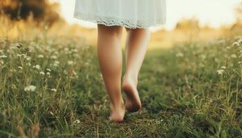 Barefoot woman walking on soft grass at sunset nature scene gentle environment low angle photo
