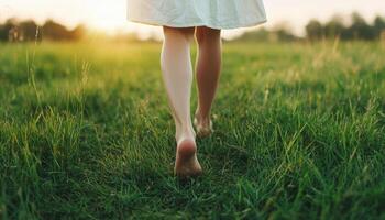 Barefoot woman walking on soft grass at sunset nature scene peaceful environment photo