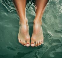Person relaxing with feet in calm river nature lifestyle serenity close-up view photo