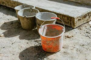A cement bucket with a red handle sitting on a cement block photo