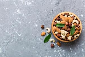 Assortment nuts wooden bowl colored table. Cashew, hazelnuts, walnuts, almonds. Mix of nuts Top view photo