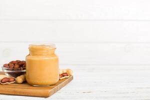 Bowl of peanut butter and peanuts on table background. top view with copy space. Creamy peanut pasta photo