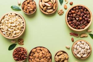 mixed nuts in wooden bowl. Mix of various nuts on colored background. pistachios, cashews, hazelnuts, peanuts and brazil nuts photo
