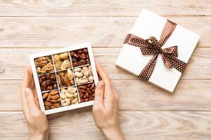 Young woman holding box with different nuts, closeup. Close up, copy space, top view, flat lay. Walnut, pistachios, hazelnuts photo