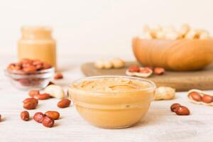 Bowl peanut butter and peanuts on table background. top view. Creamy peanut pasta photo