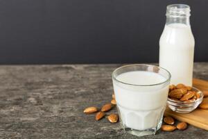 Top view almond milk in the glass bottle with almond nuts on the colored table. top view vith copy space photo