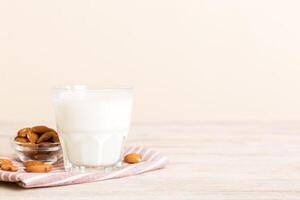 Top view the almond milk in the glass bottle with almond nuts on the colored table. top view copy space photo