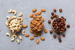 Assortment of nuts in wooden bowl on colored table. Cashew, hazelnuts, walnuts, almonds. Mix of nuts photo