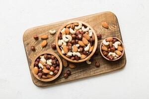 Assortment nuts in wooden bowl on colored table. Cashew, hazelnuts, walnuts, almonds. Mix of nuts Top view photo