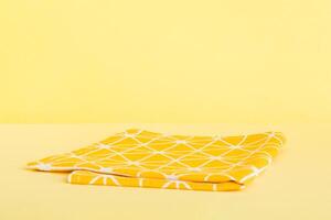 top view with yellow empty kitchen napkin isolated on table background. Folded cloth for mockup copy space, photo
