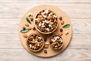 Assortment nuts wooden bowl on colored table. Cashew, hazelnuts, walnuts, almonds. Mix of nuts with copy space photo