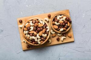 Assortment nuts wooden bowl on colored table. Cashew, hazelnuts, walnuts, almonds. Mix nuts Top view with copy space photo