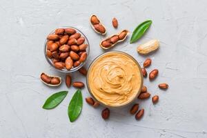 Bowl of peanut butter and peanuts on table. top view with copy space. Creamy peanut pasta in small bowl photo