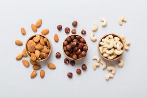 Assortment nuts in wooden bowl on colored table. Cashew, hazelnuts, walnuts, almonds. Mix nuts Top view photo