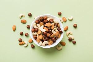 Assortment nuts wooden bowl on colored table. Cashew, hazelnuts, walnuts. Mix of nuts Top view with copy space photo