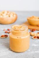Bowl of peanut butter and peanuts on table background. top view with copy space. Creamy peanut pasta small bowl photo