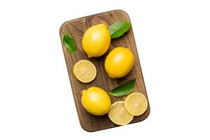 Top view with copy space for fresh and ripe lemons on cutting board. Healthy food background. Elegant background of lemon and lemon slices on white background photo