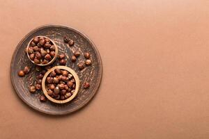 Wooden bowl full hazelnuts table background. Healthy eating concept. photo
