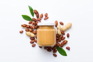 Bowl peanut butter and peanuts table background. top view . Creamy peanut pasta in small bowl photo