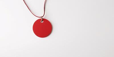 Red circular tag on a cord against a white background. photo
