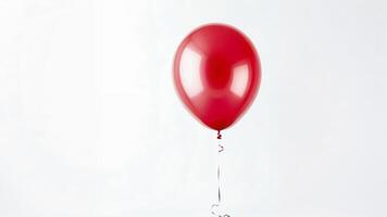 Single red balloon floating against a white background. photo