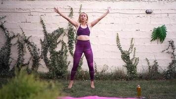 Mother demonstrates fitness routine in sunlit garden, promoting health and wellness through joyful exercise video