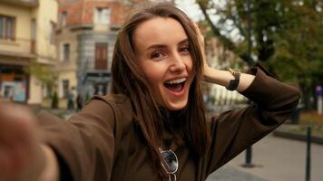 Mobile phone camera view happy smiling Caucasian woman posing smiling make selfie at street female girl in city holding smartphone call record vlog photo picture online live broadcasting stream