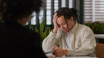 Ethnic business guy intern man male in office getting rejected for job upset back view African American leader boss giving folder with documents papers bad result two businessmen paperwork problem photo