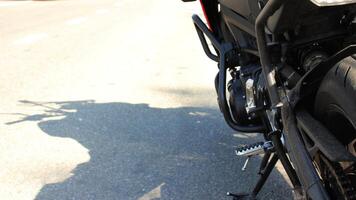 Motorcycle on a kickstand casts a shadow on asphalt road detailed stock photo