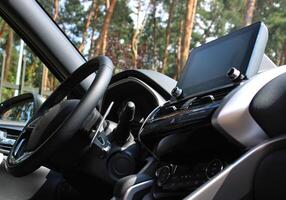 Bottom view of steering wheel and central dashboard of car parked in forest photo