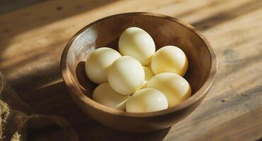 A wooden bowl filled with peeled eggs on a rustic table in natural sunlight - Generated using AI photo