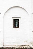barred window in old white monastery wall photo