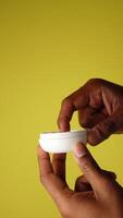 Applying petroleum jelly with hands on yellow background video