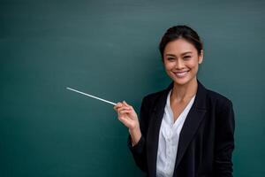 Smiling teacher points to chalkboard photo