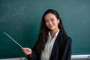 Asian teacher holding a pointer in front of a blackboard photo