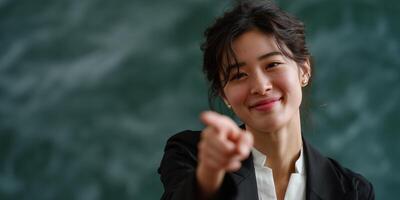 Woman pointing, smiling, and looking directly at viewer photo