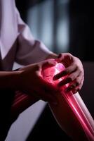 Close-up of a person's knee with glowing, highlighted bones, indicative of joint pain. Hands hold the painful knee photo