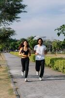 Couple jogging outdoors on paved path. Smiling, active photo