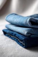 Three folded blue jeans on a white surface photo