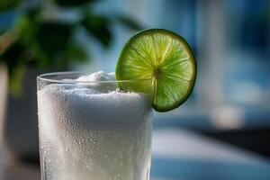 A glass of white liquid with a lime slice photo