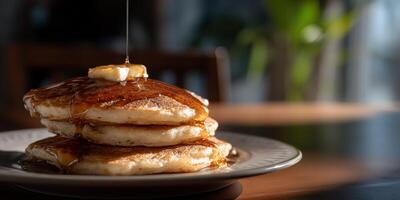 A stack of pancakes on a plate with syrup being drizzled on top photo